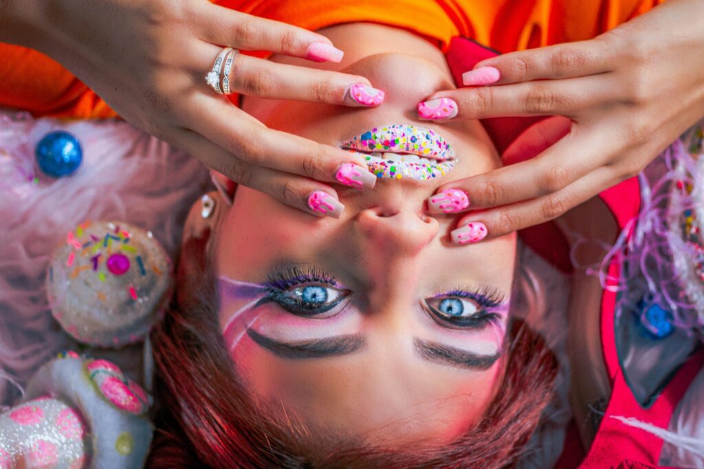 Colorful portrait of a woman with artistic makeup and nail art. Bright and creative fashion style.