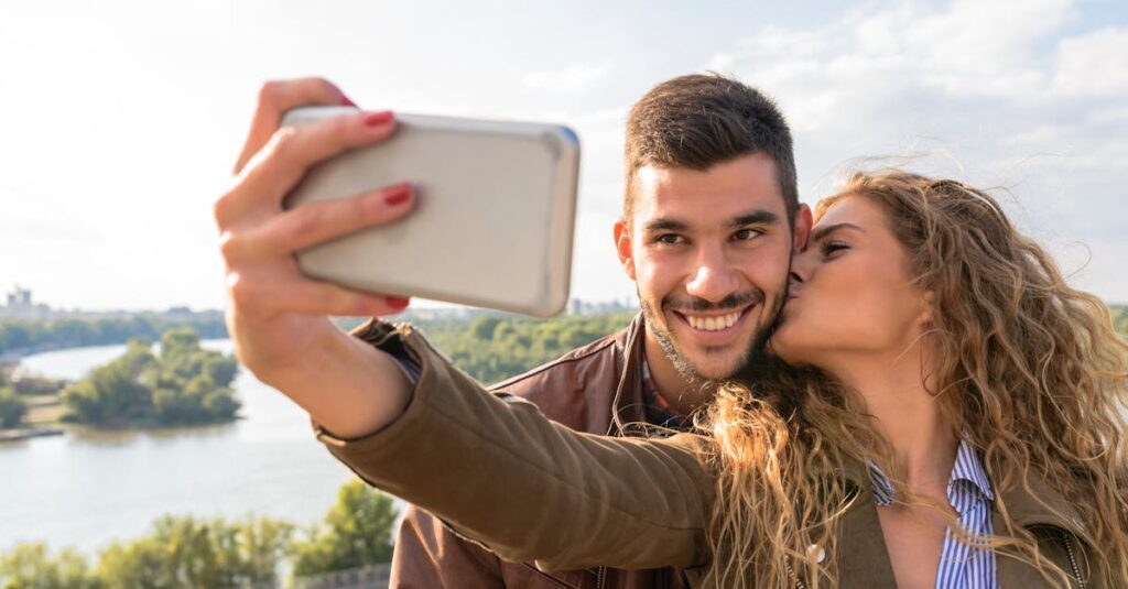 A happy couple taking a romantic selfie by the scenic riverside on a sunny day.
